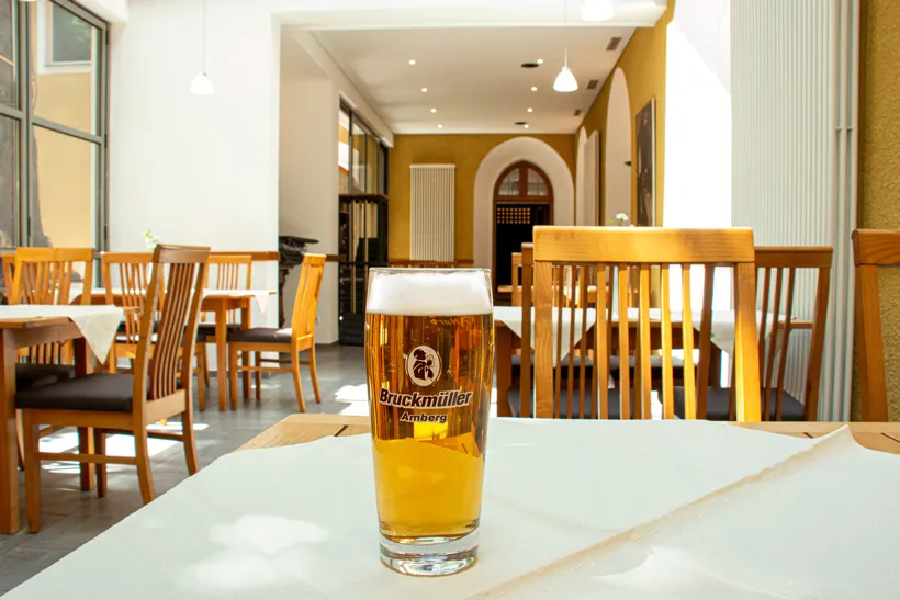 Ein Glas Bier steht auf einem Tisch mit weißer Tischdecke.